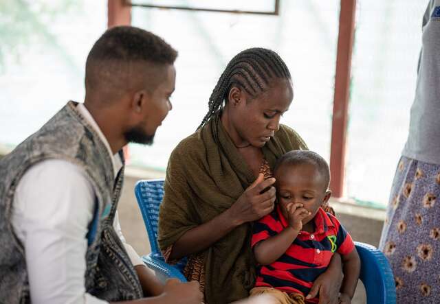 A woman holding her child on her lap and looking at him.