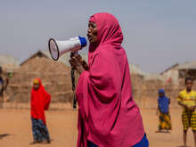 En kvinna pratar in i en megafon på landsbygden i Ethiopien. 