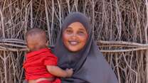 24 January 2024, Dadaab Refugee Camp, Kenya. Fatuma, who is 25 years old, stands outside her home with her son.