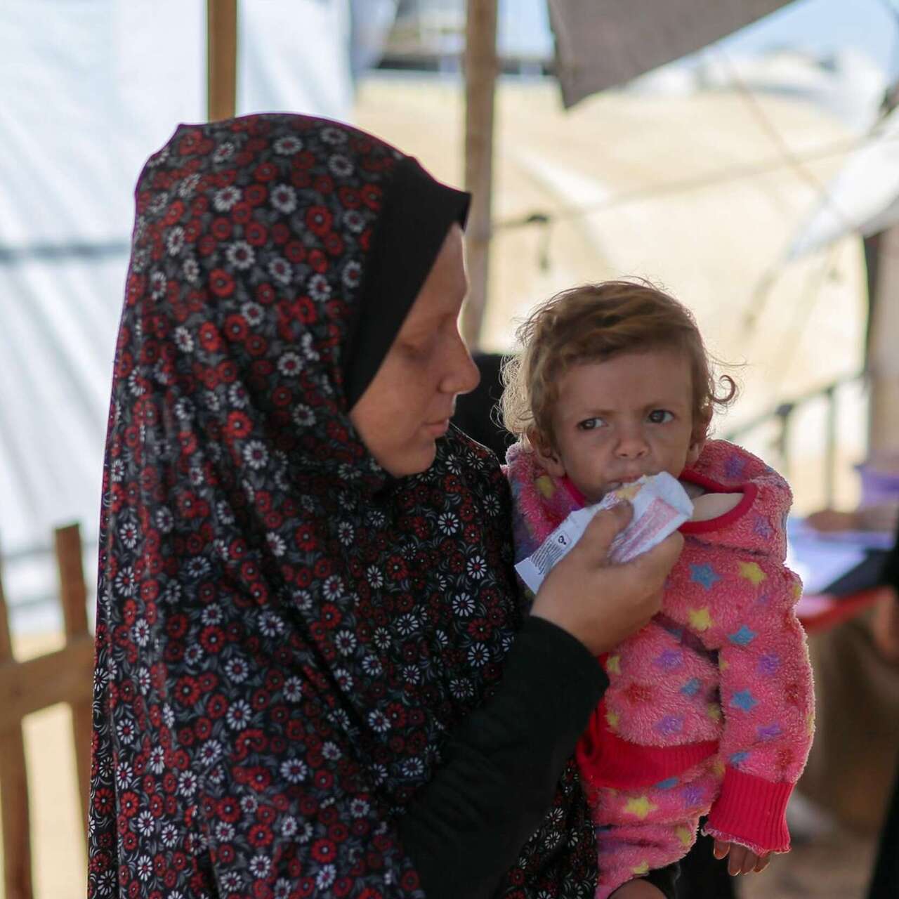 국제구조위원회 영양실조 치료센터에서 한 여성이 어린이에게 영양실조 치료식을 먹이고 있습니다.