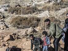 A family walks through an arid landscape with their belongings.