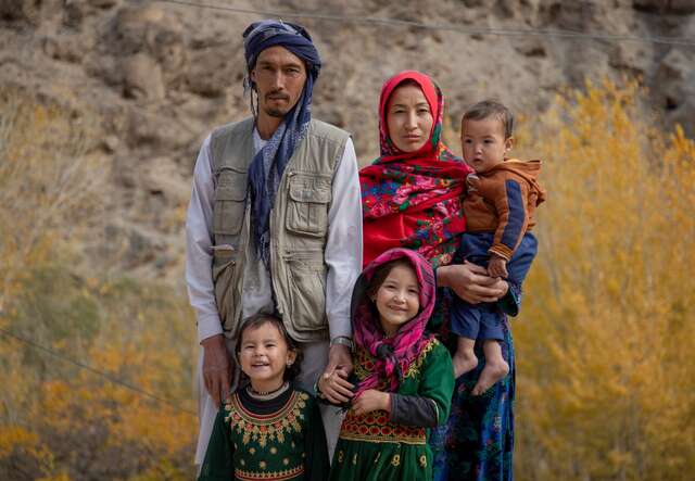 An Afghan family of five pose for a family portrait outside their home in rural Afghanistan.