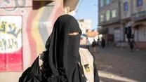 Tahani is fully veiled and is walking in a street